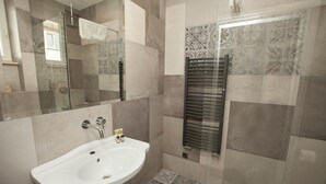 A bathroom with a white sink, a glass shower enclosure, and a towel rack. - Comfort Art by Grand Apartments (Sopot)