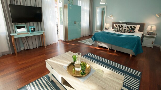 A modern hotel room with a bed, a TV, a desk, and a coffee table. - Comfort Art by Grand Apartments (Sopot)