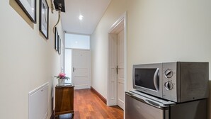 A narrow hallway with a wooden floor, a white door, and a refrigerator with a built-in microwave. - Comfort Art by Grand Apartments (Sopot)