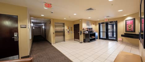 A hotel lobby with an elevator, a reception desk, and a seating area.