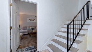 A staircase with a black handrail leading to a landing. - Grad Basecamp | Pet-Friendly 2BR (Columbus)