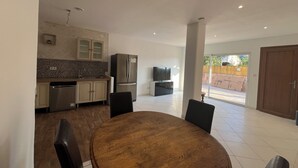 A spacious living area with a dining table, chairs, a kitchen with modern appliances, and a TV. - Bas de Villa Oasis (Sainte maxime)