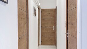A hallway with wooden doors and white tiled flooring. - Bas de Villa Oasis (Sainte maxime)
