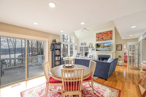A spacious living room with a fireplace, a large window overlooking a deck, and a cozy seating area.