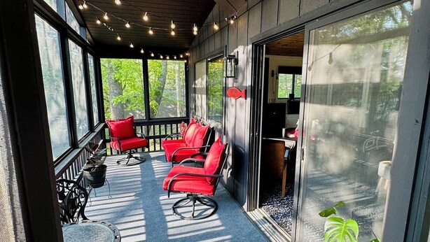Eine überdachte Terrasse mit roten Stühlen, einem Tisch und Lichterketten.