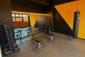 Une salle de sport équipée de matériel de musculation, de bancs et d’un sac de frappe.
