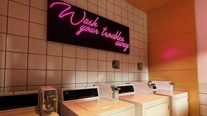 Uma área de lavanderia com uma placa de neon que diz 'Lave suas preocupações.
