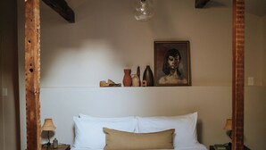 A bedroom with a skylight, a bed with white linens, a wooden headboard, and a nightstand with a lamp. - Kingston Carriage House (Kingston)