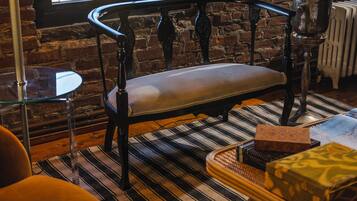 A cozy room with a bench, a small table, a lamp, and a painting on the wall.