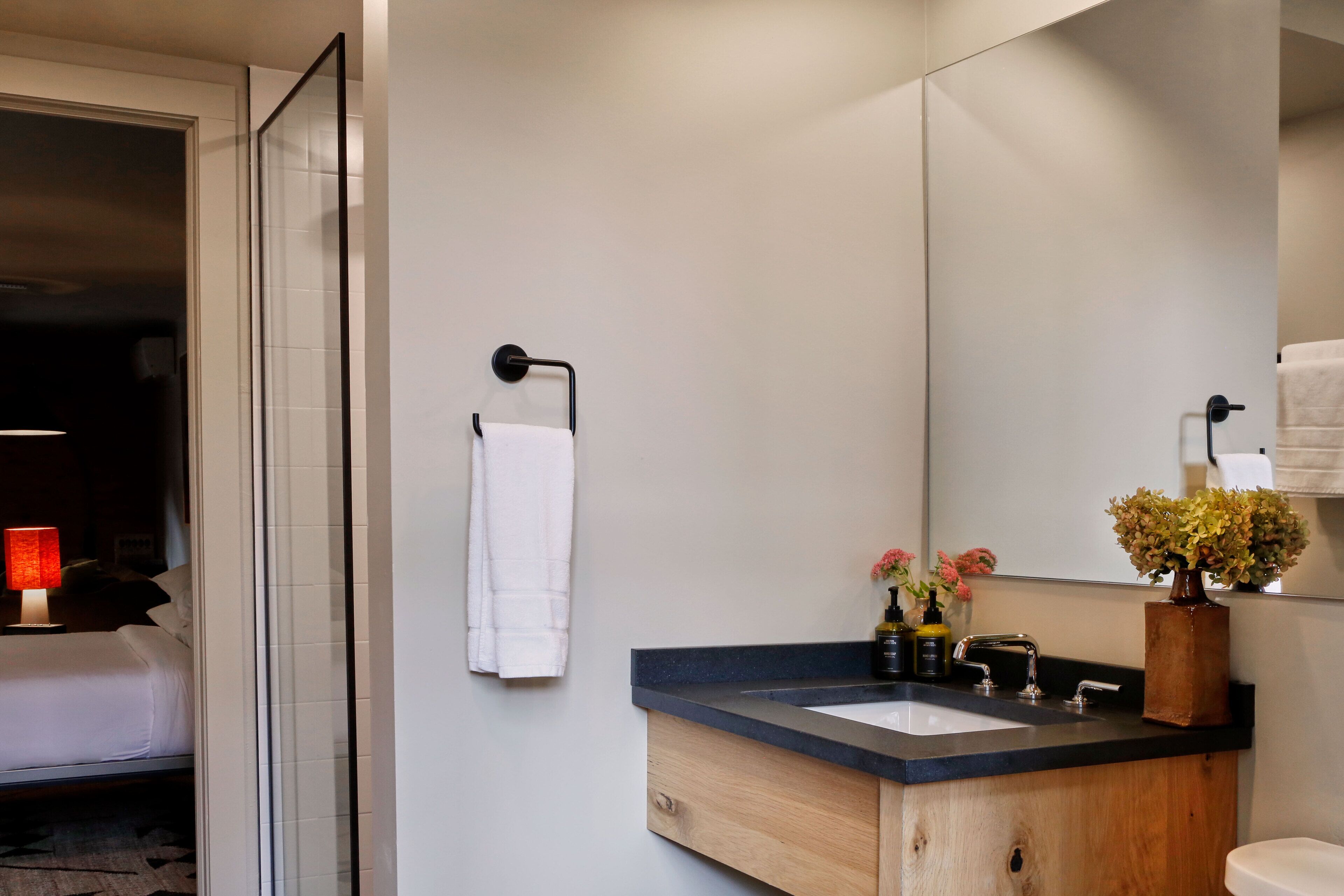A modern bathroom with a wooden vanity, a large mirror, and a white sink.