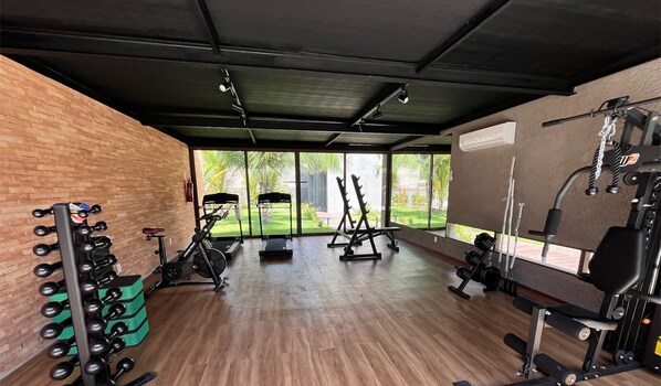 Et træningscenter med træningsudstyr, store vinduer og en murstensvæg.