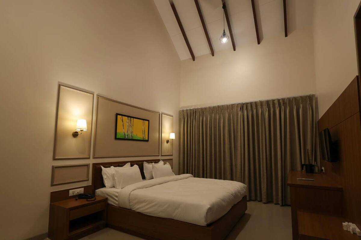 Une chambre d’hôtel avec un lit, des tables de chevet, une télévision et un tableau au mur.