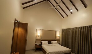 A hotel room with a bed, a wooden wardrobe, a ceiling fan, and a large mirror. - Baba (Nandurbar)