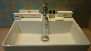 A bathroom sink with a shower head, a comb, a toothbrush, and a bottle of mouthwash. - Baba (Nandurbar)