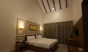 A hotel room with a bed, bedside tables, a TV, and a painting on the wall. - Baba (Nandurbar)