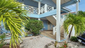 A two-story building with a blue exterior and white railings. There is a staircase leading to the upper level.