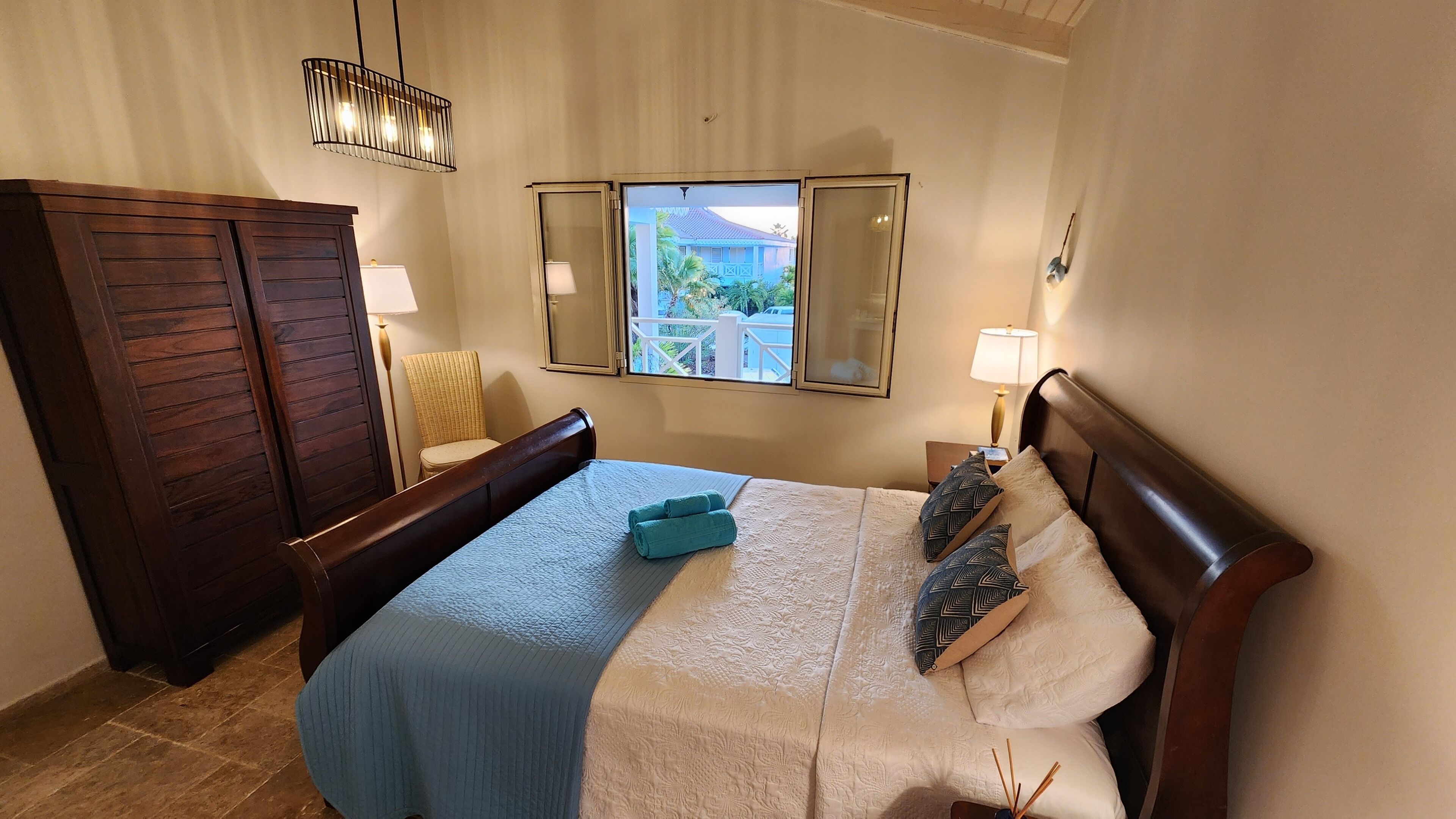 Hotelkamer met een bed, een stoel, een kledingkast, een raam met uitzicht en een hanglamp.