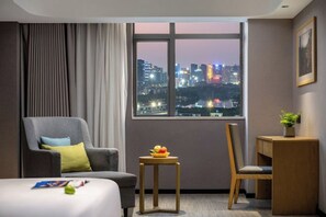 A hotel room with a city view, a bed, a desk, and a chair. - Parlor Hotel (Dongguan)