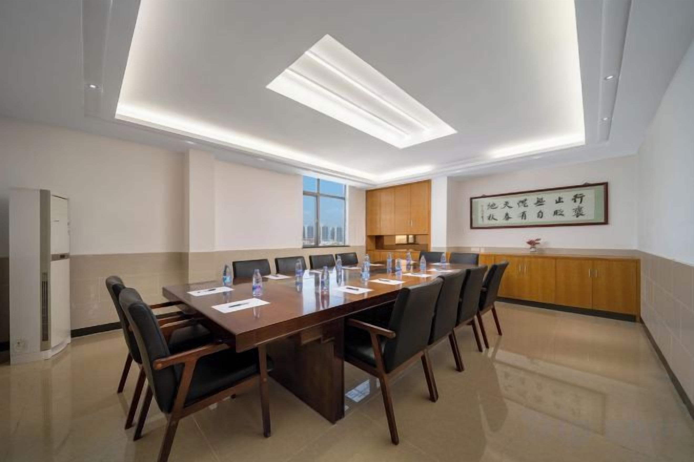 A conference room with a long table, chairs, and a ceiling light fixture.