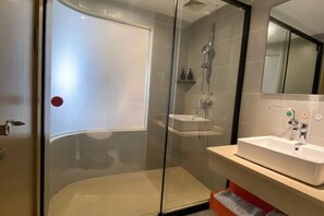 A modern bathroom with a glass-enclosed shower, a white sink, and a mirror above it. - Parlor Hotel (Dongguan)