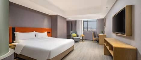 A hotel room with a large bed, a desk, a chair, and a TV mounted on the wall.