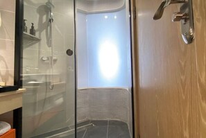 A glass-enclosed shower area with a tiled floor, a showerhead, and a visible towel rack. - Parlor Hotel (Dongguan)