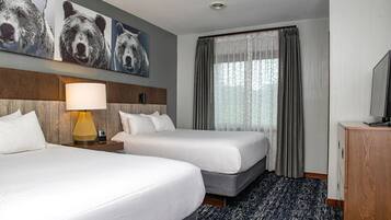 Une chambre d’hôtel avec deux lits, une lampe, un téléviseur et un tableau représentant des ours accroché au mur.