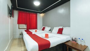 Een hotelkamer met twee bedden, rode en witte beddengoed, een houten nachtkastje met waterflesjes, en een rood gordijn.