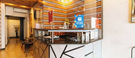 A reception desk with a modern design, a wooden ceiling, and a clear glass partition.