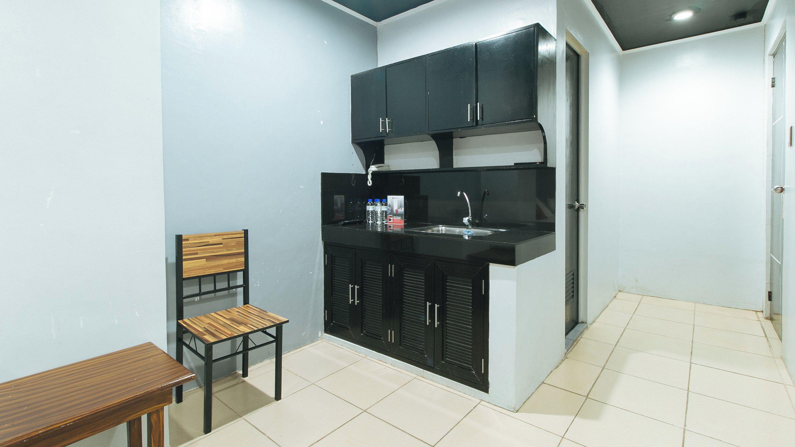 A compact kitchen with black cabinets, a wooden chair, and a small table.