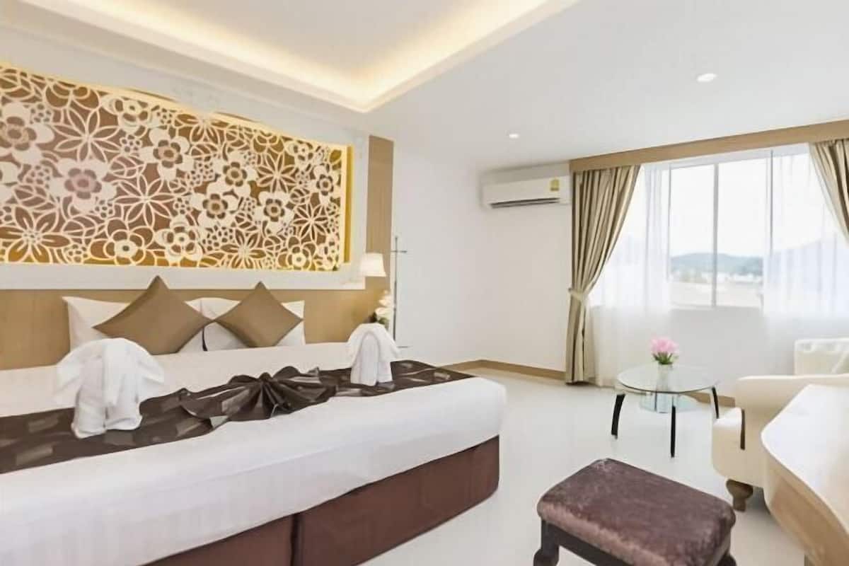 A hotel room with a bed, a small round table, a sofa, and a decorative wall panel.