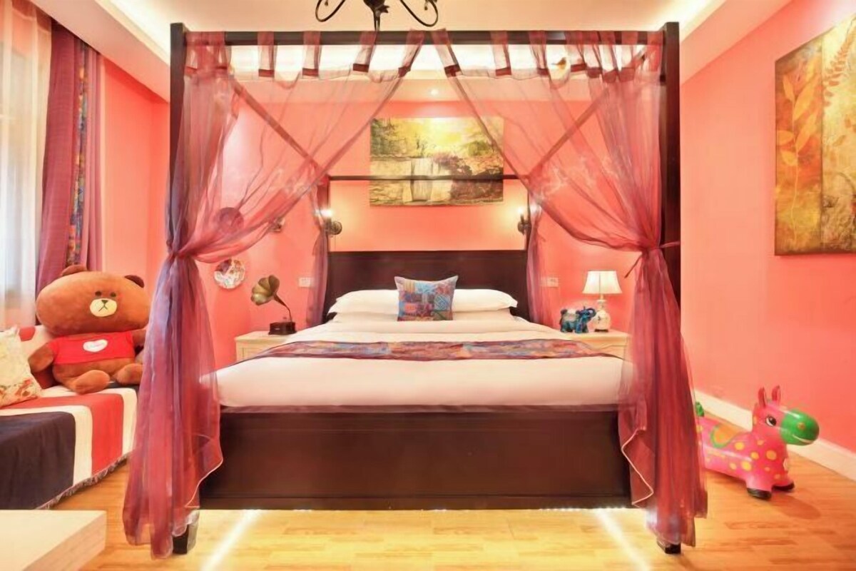 Un dormitorio con una cama con dosel, un oso de peluche y un caballo de juguete.