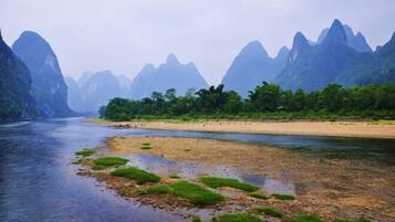 Um rio com uma praia arenosa e vegetação verde, cercado por montanhas.