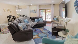 A living room with a brown sofa, teal armchair, and a patterned rug. - Casa Bay-Spacious Family Friendly 4 Bedroom Home with Ultimate Backyard Fun! (Cutler Bay)