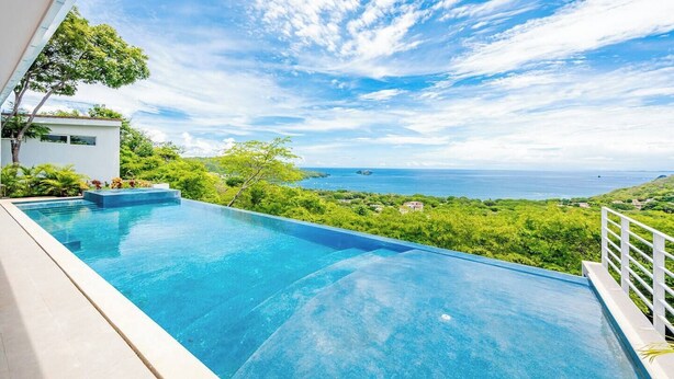 Ein moderner Infinity-Pool mit freiem Blick auf den Ozean und üppiger Vegetation.