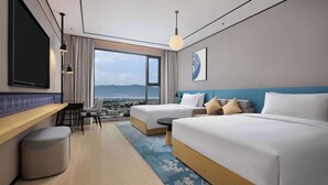 A hotel room with a large bed, a desk, and a view of the city. - Hilton Garden Inn Dali Ancient City (Dali)