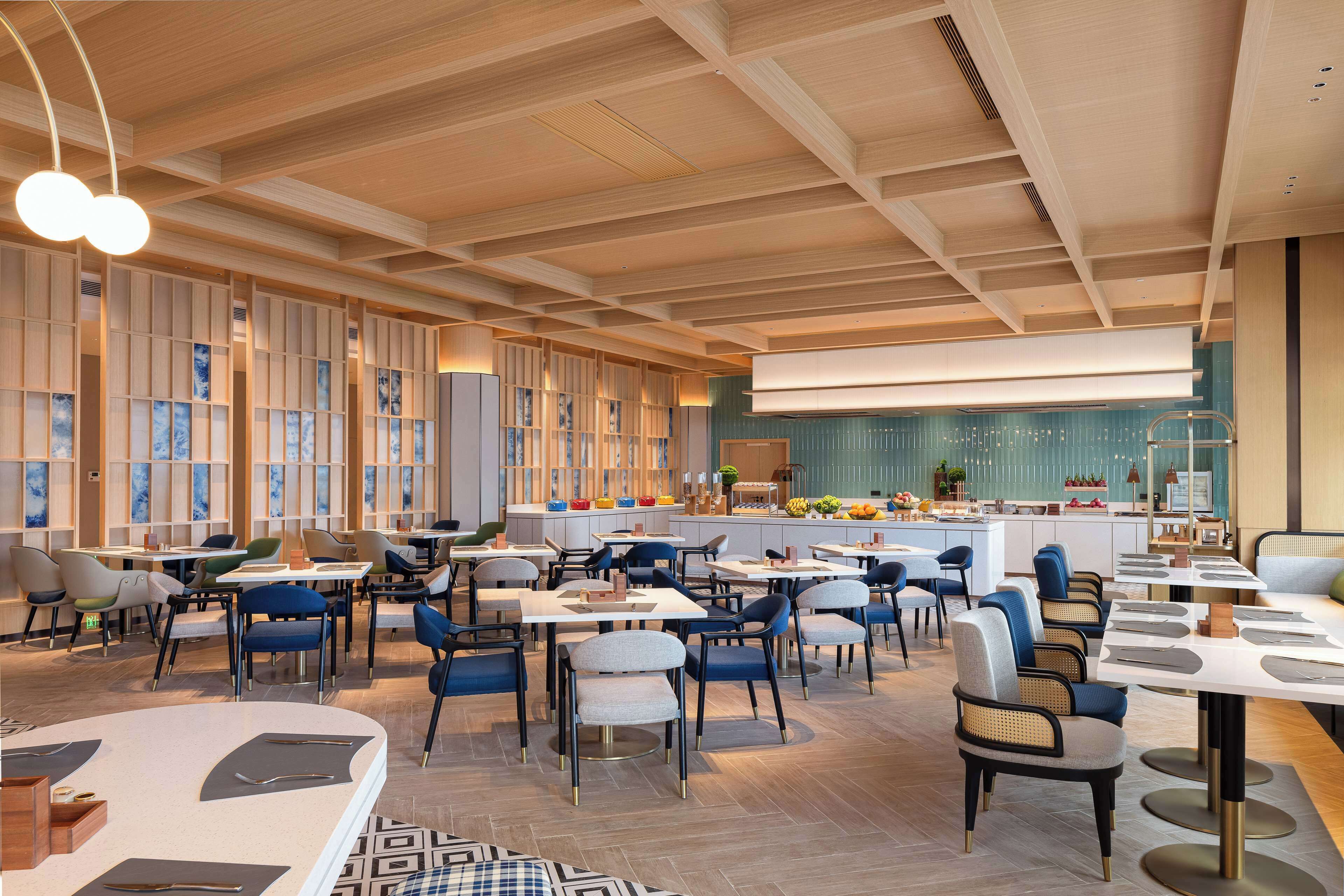 A modern restaurant with a variety of seating options, including tables and booths, and a central bar area.