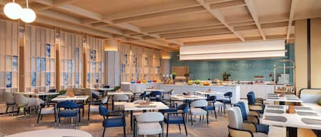 Ein modernes Restaurant mit verschiedenen Sitzgelegenheiten, darunter Tische und gemütliche Nischen, sowie einer zentralen Bar.