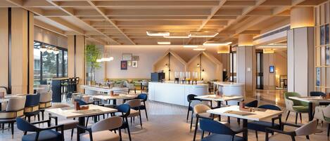 Un comedor amplio con varias mesas y sillas, una barra central, y grandes ventanales que proporcionan luz natural.