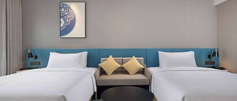 A hotel room with two beds, a sofa, a round table, and a wall-mounted artwork.