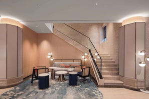 A modern hotel lobby with a staircase, seating area, and a view of the sky. - Hilton Garden Inn Dali Ancient City (Dali)
