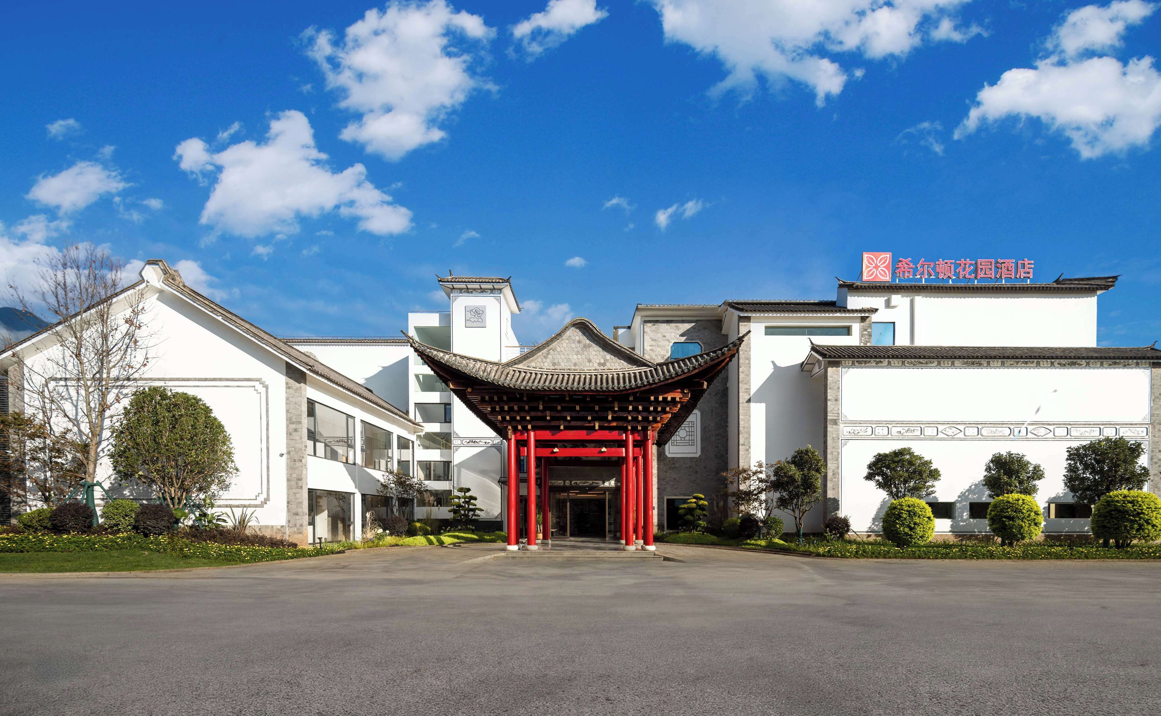 A traditional Chinese building with a red gate, modern architecture, and a clear blue sky.