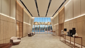 Un vestíbulo amplio con vista a la piscina, muebles modernos y una estación de café.