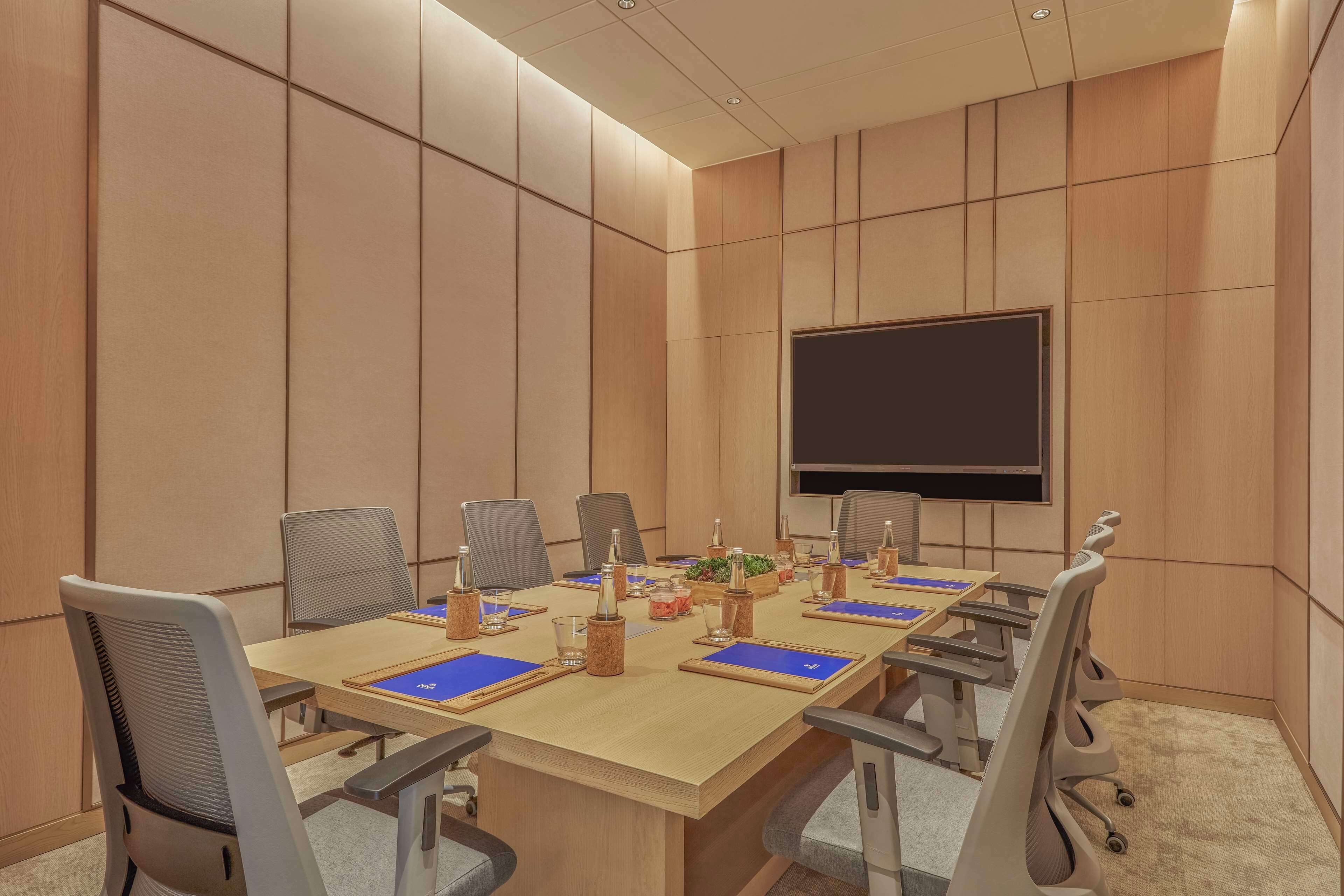 A conference room with a long table, chairs, a projector screen, and a whiteboard.