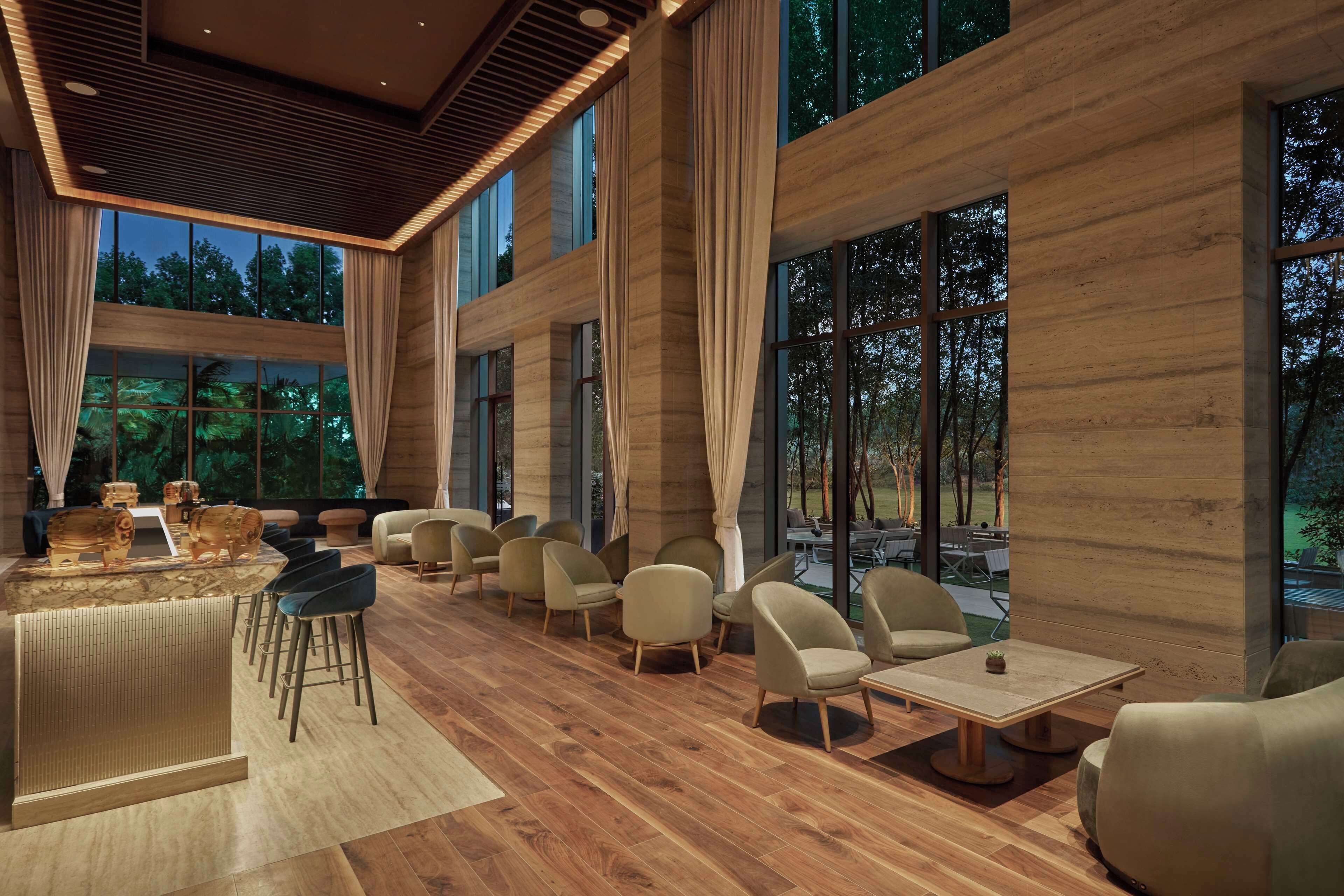 A modern interior with a bar area, seating, and large windows offering views of the outdoors.