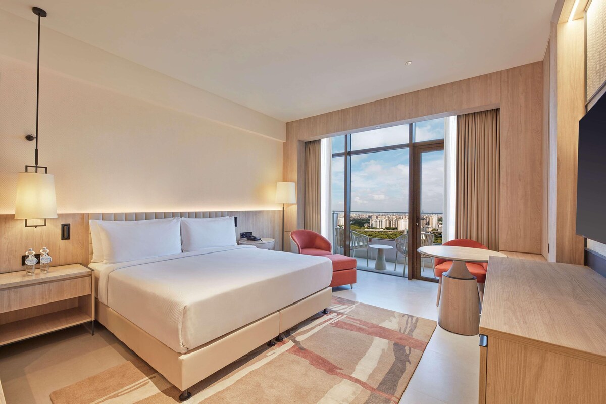 Une chambre d’hôtel moderne dotée d’un grand lit, d’un bureau, d’une chaise et d’un balcon avec vue.