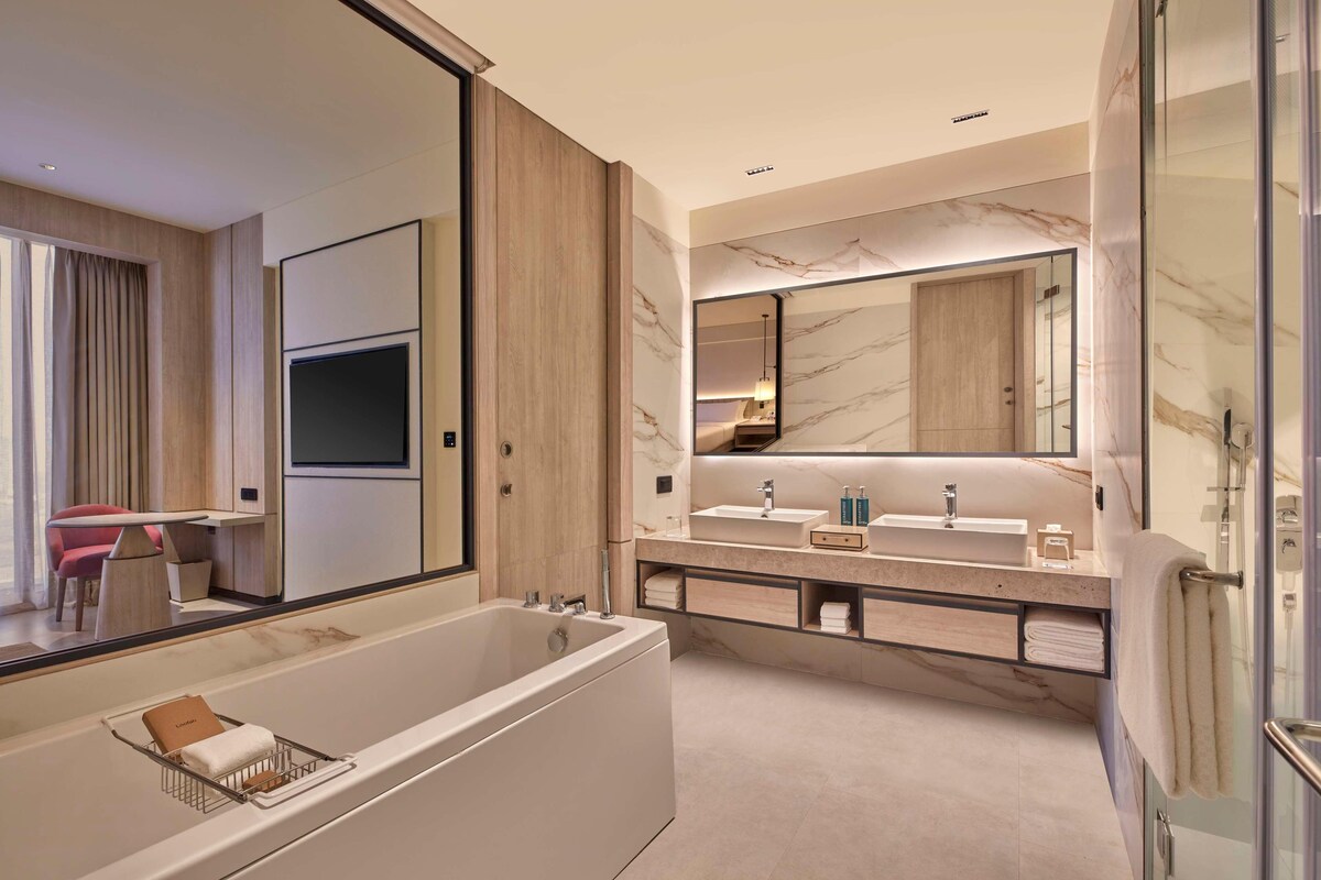 Une salle de bain moderne avec une grande baignoire, un meuble-lavabo doté de deux vasques et un grand miroir.