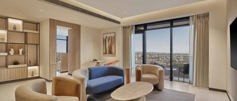 Una sala de estar moderna con un sofá, sillones y una mesa de centro. Se ve una ventana grande con vista a la ciudad.