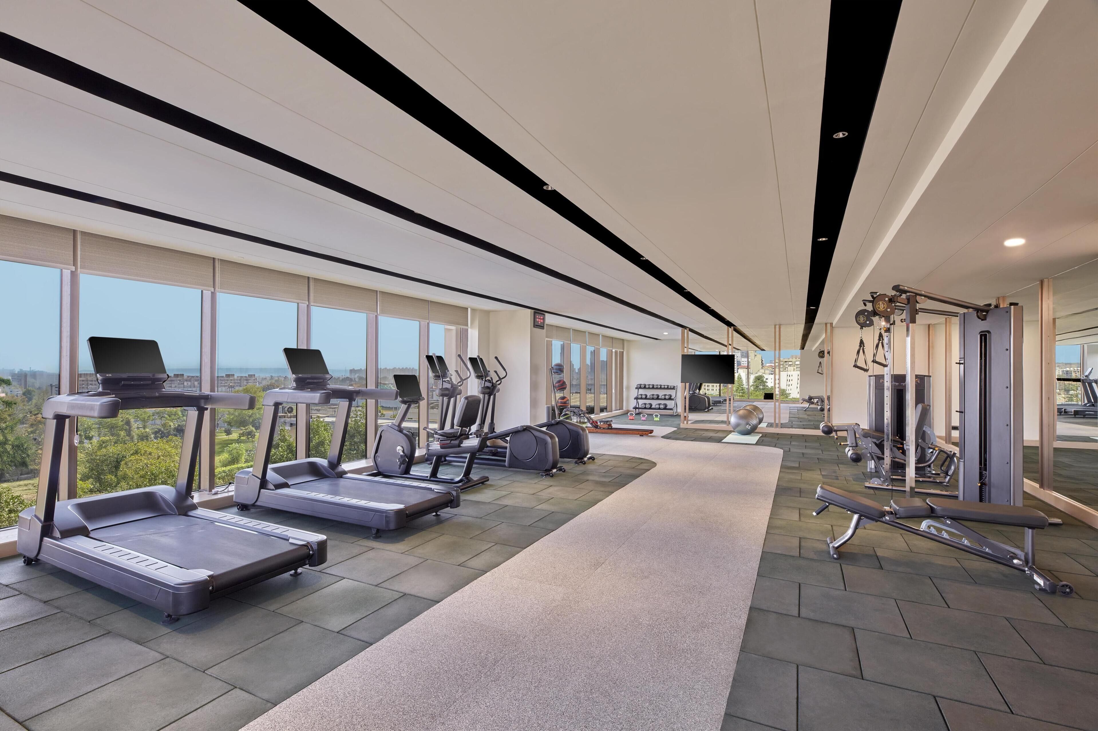 Un gimnasio moderno con cintas de correr, elípticas y equipo de levantamiento de pesas.