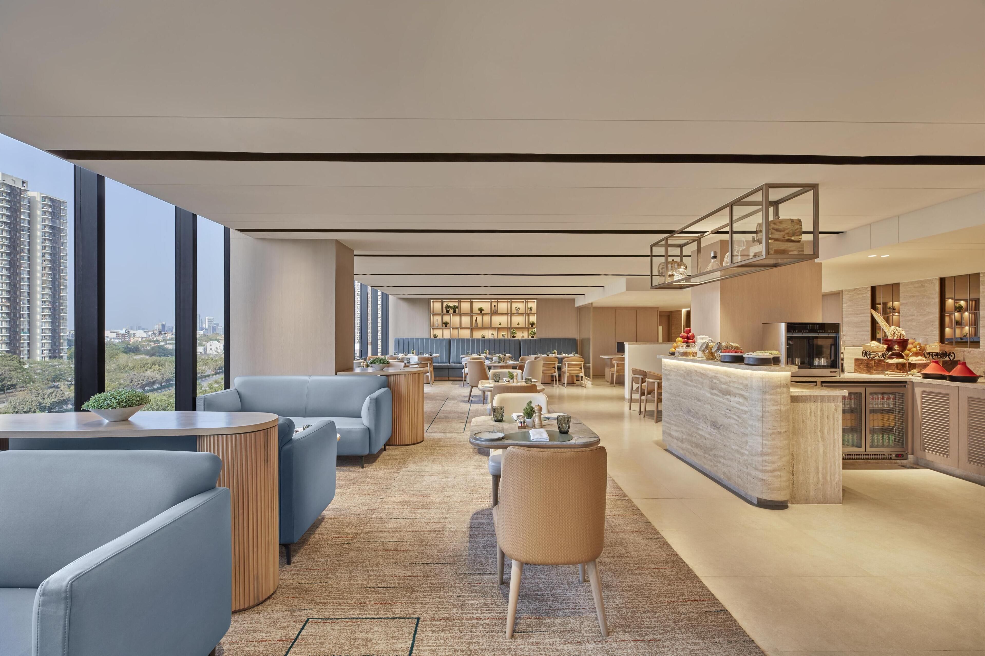 Un hall d’hôtel moderne doté d’espaces de détente, d’un bar et d’une cuisine.